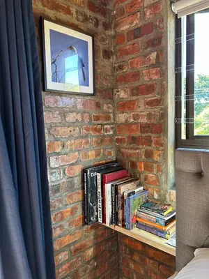 a brick wall with a shelf with books at Garden Studio in Greyton
