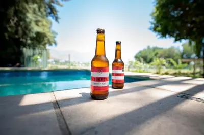 two bottles of beer sitting on a table next to a pool at Franschhoek Homestead Cottage in Groendal