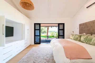 a bedroom with a large bed and a flat screen tv at Franschhoek Homestead Cottage in Groendal