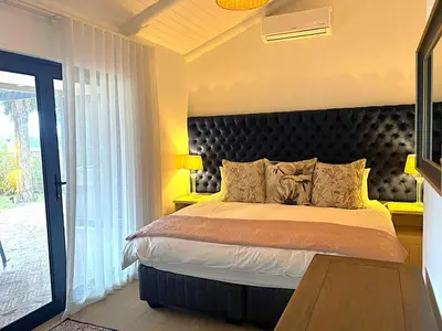 a bedroom with a bed with a large headboard at Franschhoek Homestead Cottage in Groendal