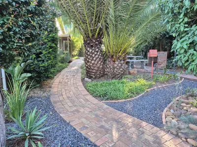 a brick walkway in a garden with a palm tree at Mistys Apartment Durbanville in Durbanville