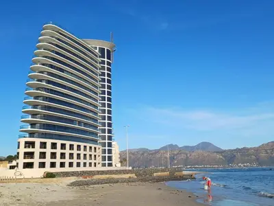 a tall building on the beach next to the ocean at Loddey's Self Catering Apartments - by Beach Collection in Strand