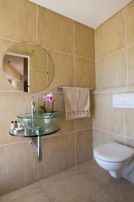 a bathroom with a sink and a toilet and a mirror at Loddey's Self Catering Apartments - by Beach Collection in Strand