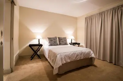 a bedroom with a bed and two lamps and a window at Loddey's Self Catering Apartments - by Beach Collection in Strand