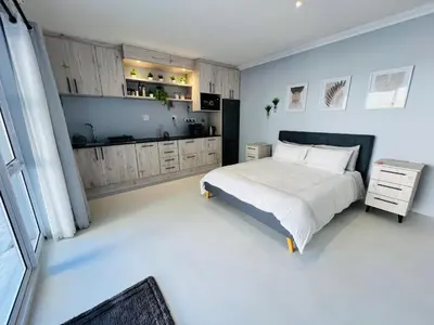 a bedroom with a large bed and a kitchen at Rissie's Place in Gordonʼs Bay