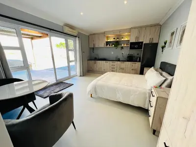 a bedroom with a bed and a table and chairs at Rissie's Place in Gordonʼs Bay