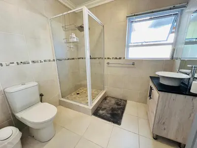 a bathroom with a shower and a toilet and a sink at Rissie's Place in Gordonʼs Bay
