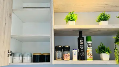 a cupboard with bottles and potted plants on it at Rissie's Place in Gordonʼs Bay