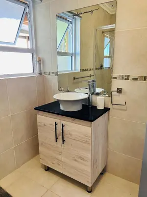 a bathroom with a sink and a mirror at Rissie's Place in Gordonʼs Bay