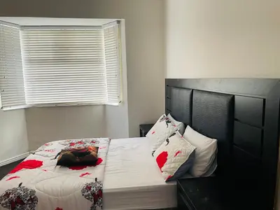 a bedroom with a bed with a black headboard and pillows at ANNIKA B&B Claremont in Cape Town