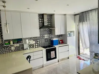 a kitchen with white cabinets and black and white tiles at ANNIKA B&B Claremont in Cape Town
