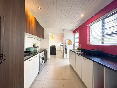 a kitchen with red walls and a counter top at Spacious Shared 3-Bedroom Villa Near Bloubergstrand Beach with Pool & Free Wi-Fi in Cape Town
