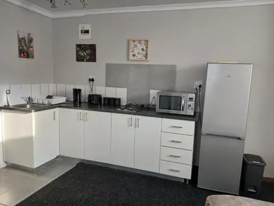 a kitchen with white cabinets and a refrigerator at Cozy, self-catering Garden Flat in Cape Town