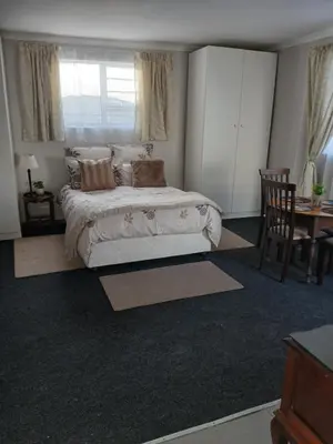 a bedroom with a bed and a table and chairs at Cozy, self-catering Garden Flat in Cape Town