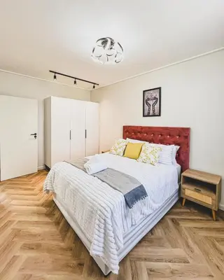 a bedroom with a large bed and a wooden floor at Bethany Apartment ON PARK Century City in Cape Town