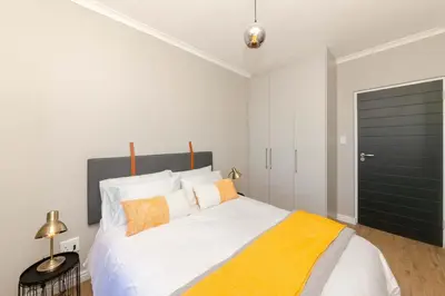a bedroom with a large white bed with orange pillows at Cape on Porterfield in Cape Town