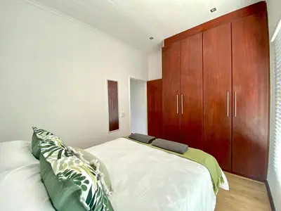 a bedroom with a bed and a wooden cabinet at Peaceful 2-Bed Apartment in Boubergstrand in Cape Town