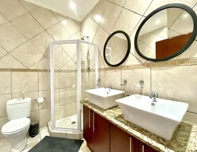 a bathroom with two sinks and a toilet and a mirror at Peaceful 2-Bed Apartment in Boubergstrand in Cape Town