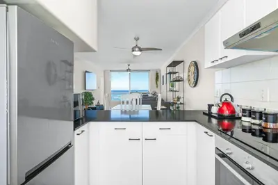 a kitchen with white cabinets and a view of the ocean at Odeon Towers 808 by Host Agents in Cape Town