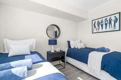 two beds in a white room with a mirror at Odeon Towers 808 by Host Agents in Cape Town