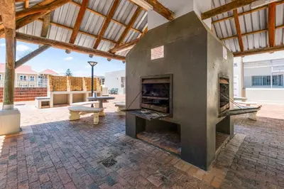 a large stone fireplace in a patio with benches at Odeon Towers 808 by Host Agents in Cape Town