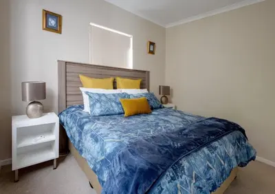 a bedroom with a bed with blue and yellow pillows at Whale - a - While in Hermanus