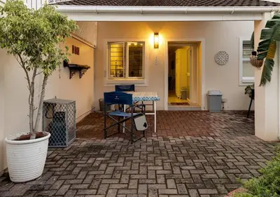 a patio with a table and chairs in front of a house at Whale - a - While in Hermanus