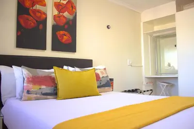 a bedroom with a white bed with yellow pillows at Tyger Classique Self-Catering Cape Town, Tyger Valley in Bellville