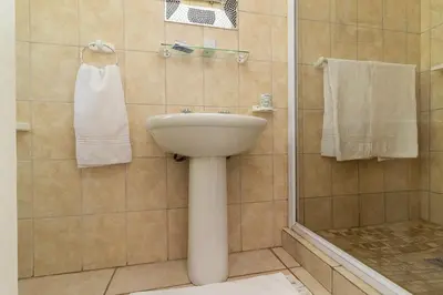 a bathroom with a sink and a shower with towels at Tyger Classique Self-Catering Cape Town, Tyger Valley in Bellville