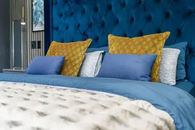 a blue bed with yellow and blue pillows on it at Red River Valley in Rooiels