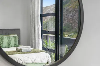 a mirror reflecting a bedroom with a bed and a window at Red River Valley in Rooiels