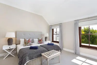 a white bedroom with two beds and a window at Winelands Golf Lodges 17 in Stellenbosch
