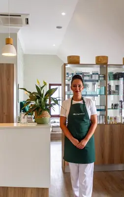 a woman wearing a green apron standing in a kitchen at Winelands Golf Lodges 17 in Stellenbosch