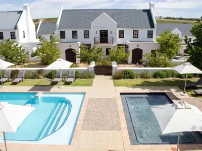a house with a swimming pool and umbrellas at Winelands Golf Lodges 17 in Stellenbosch