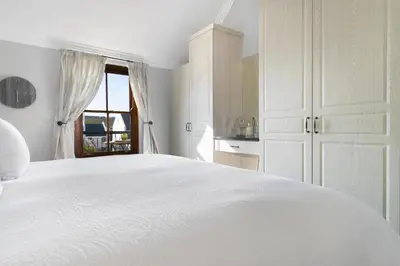 a white bedroom with a white bed and a window at Winelands Golf Lodges 20 in Stellenbosch