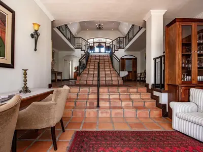a hallway with a staircase with chairs and a couch at Winelands Golf Lodges 20 in Stellenbosch