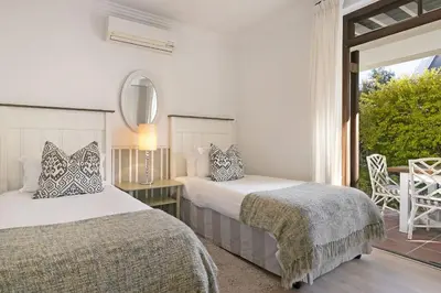two beds in a white room with a window at Winelands Golf Lodges 22 in Stellenbosch