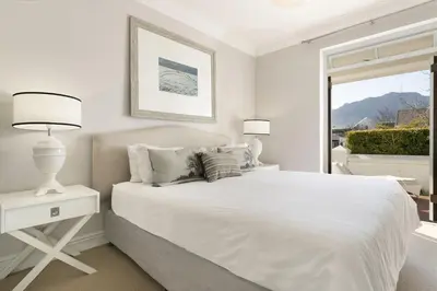 a white bedroom with a white bed and a window at Winelands Golf Lodges 33 in Stellenbosch