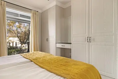 a bedroom with a bed with a yellow blanket on it at Winelands Golf Lodges 37 in Stellenbosch