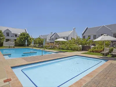 a large swimming pool in a yard with houses at Winelands Golf Lodges 37 in Stellenbosch