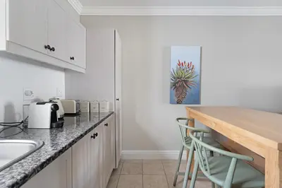 a kitchen with white cabinets and a counter with stools at Winelands Golf Lodges 38 in Stellenbosch