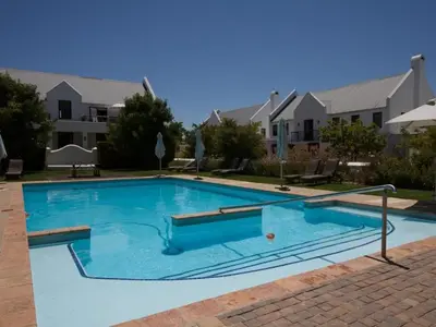 a large blue swimming pool in front of a building at Winelands Golf Lodges 38 in Stellenbosch