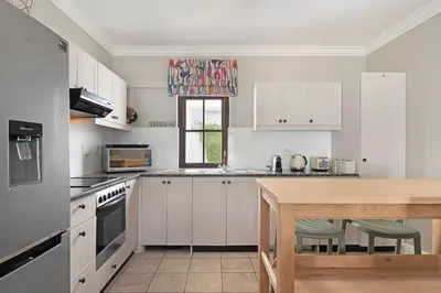 a kitchen with white cabinets and a wooden table at Winelands Golf Lodges 38 in Stellenbosch