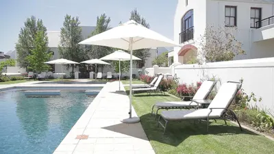 a group of chairs and an umbrella next to a pool at Winelands Golf Lodges 40 in Stellenbosch