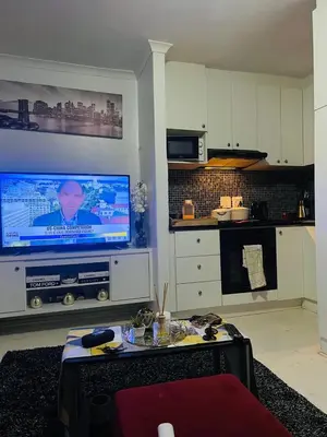 a living room with a flat screen tv and a kitchen at One Bedroom Loevenstein in Tygerberg Hills