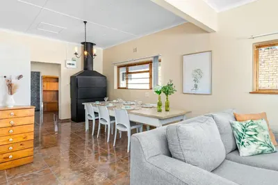 a living room with a gray couch and a table at The Kleinmond Cottage in Kleinmond