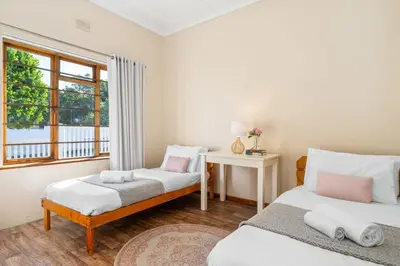 a room with two beds and a table and a window at The Kleinmond Cottage in Kleinmond