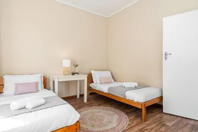 a bedroom with two beds and a table with a rug at The Kleinmond Cottage in Kleinmond