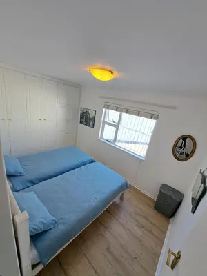 a bedroom with a blue bed and a window at Stunning 3 Bedroom beach house in Bloubergstrand in Cape Town