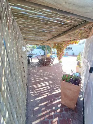 a patio with a table and chairs and a wall at Stunning 3 Bedroom beach house in Bloubergstrand in Cape Town